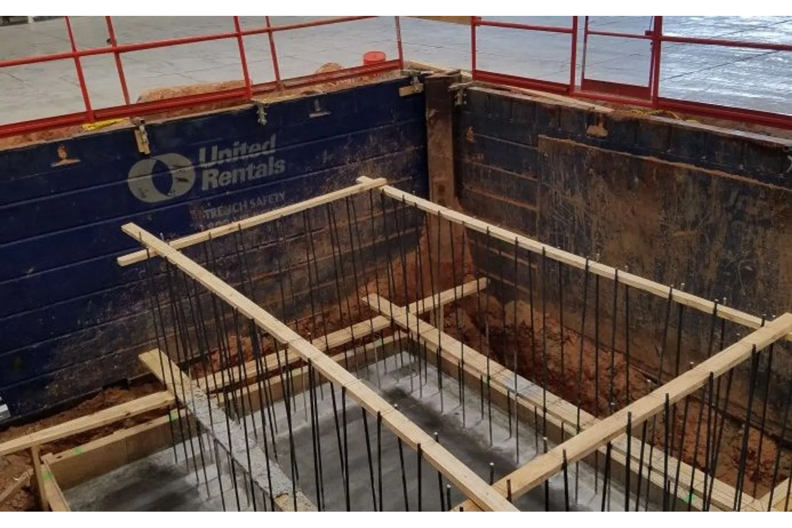 Concrete foundation rebar framework inside excavation supported by wooden braces at construction site