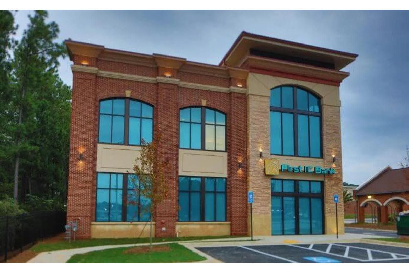 Modern two-story First FC Bank building with large windows and brick facade during early evening.