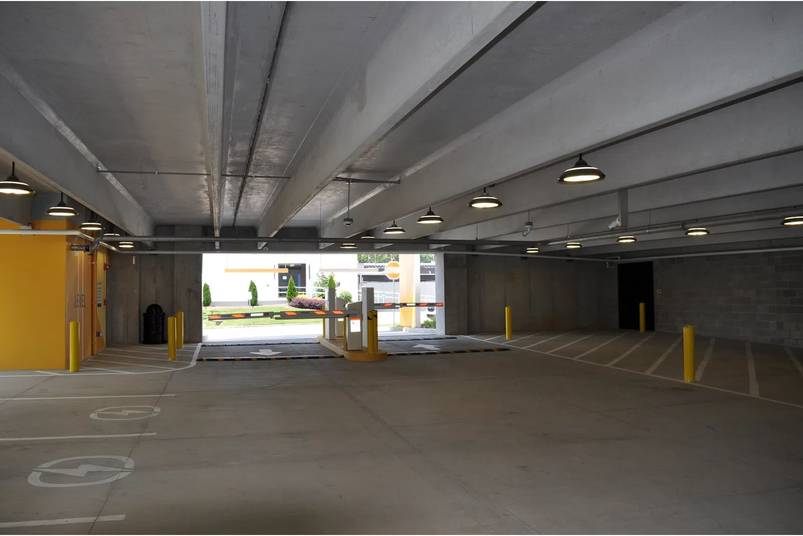 Interior view of an empty underground parking garage with concrete structure and yellow barriers.