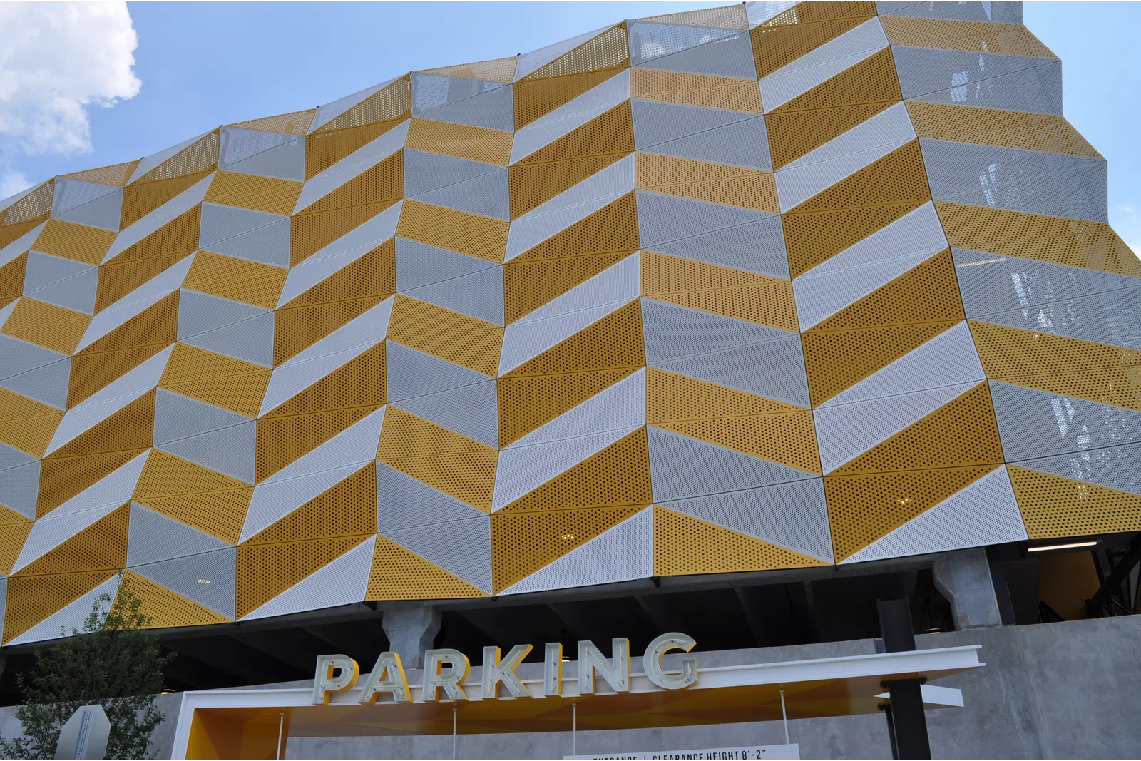 Modern parking garage with geometric yellow and white patterned facade under blue sky.