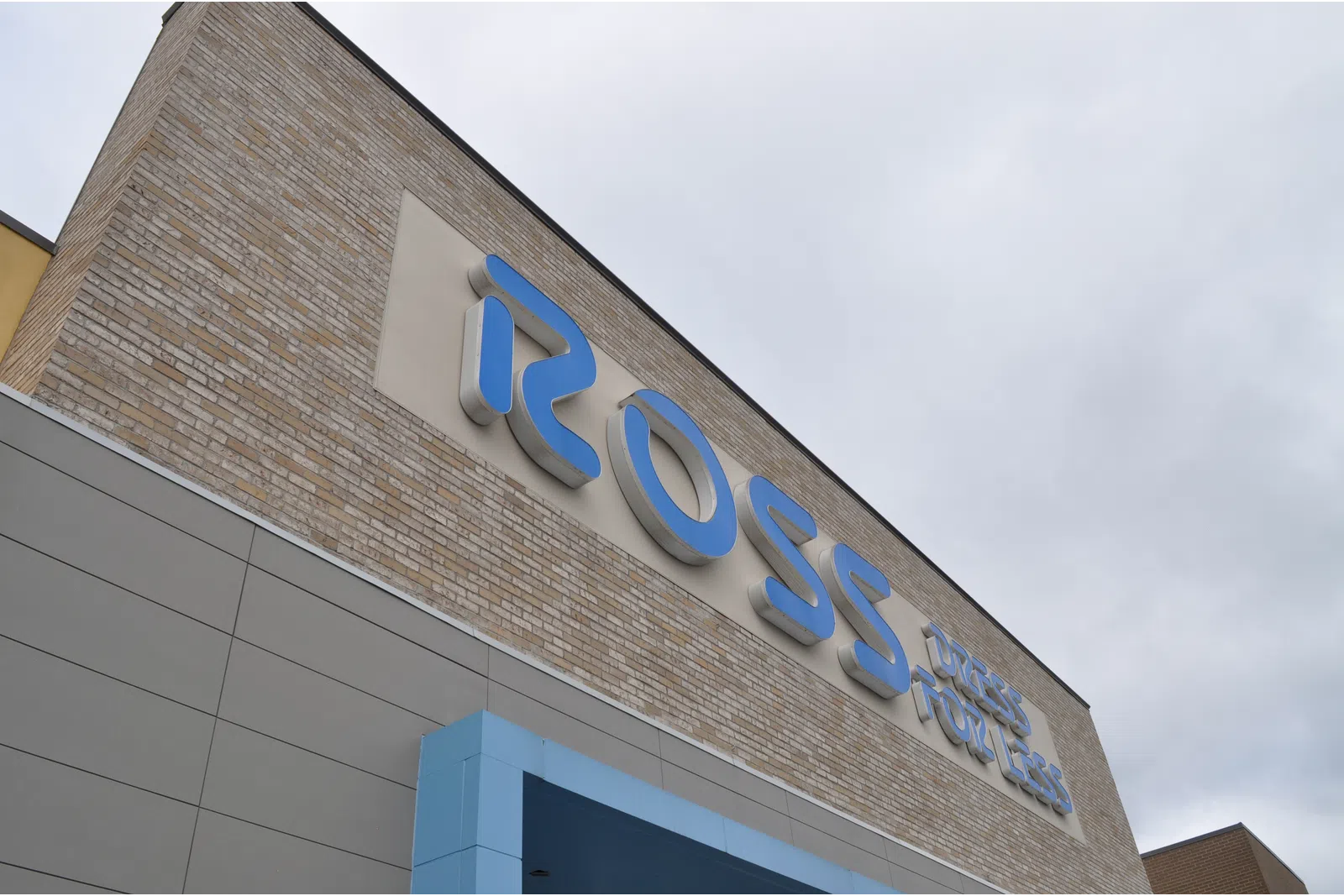 Blue Ross Dress for Less sign on a brick and gray store exterior under cloudy sky.