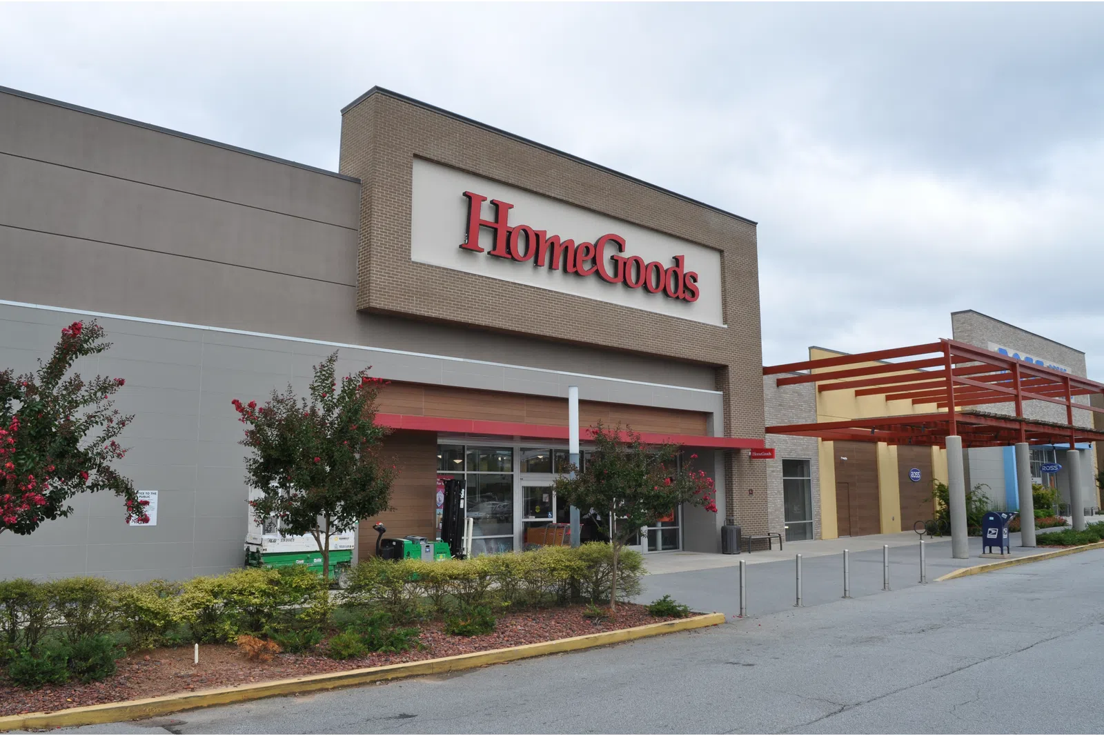 Exterior view of a HomeGoods store with clear signage and landscaped entrance under a cloudy sky.