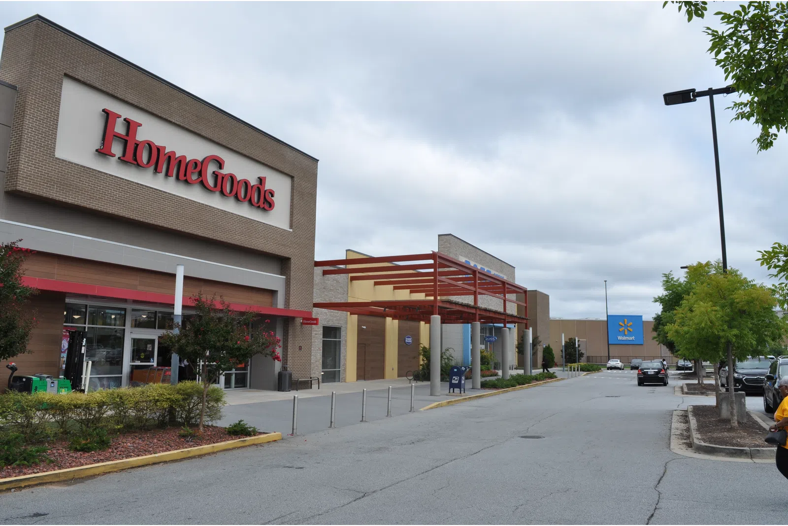 Exterior view of HomeGoods store next to Walmart in a shopping plaza under a cloudy sky.