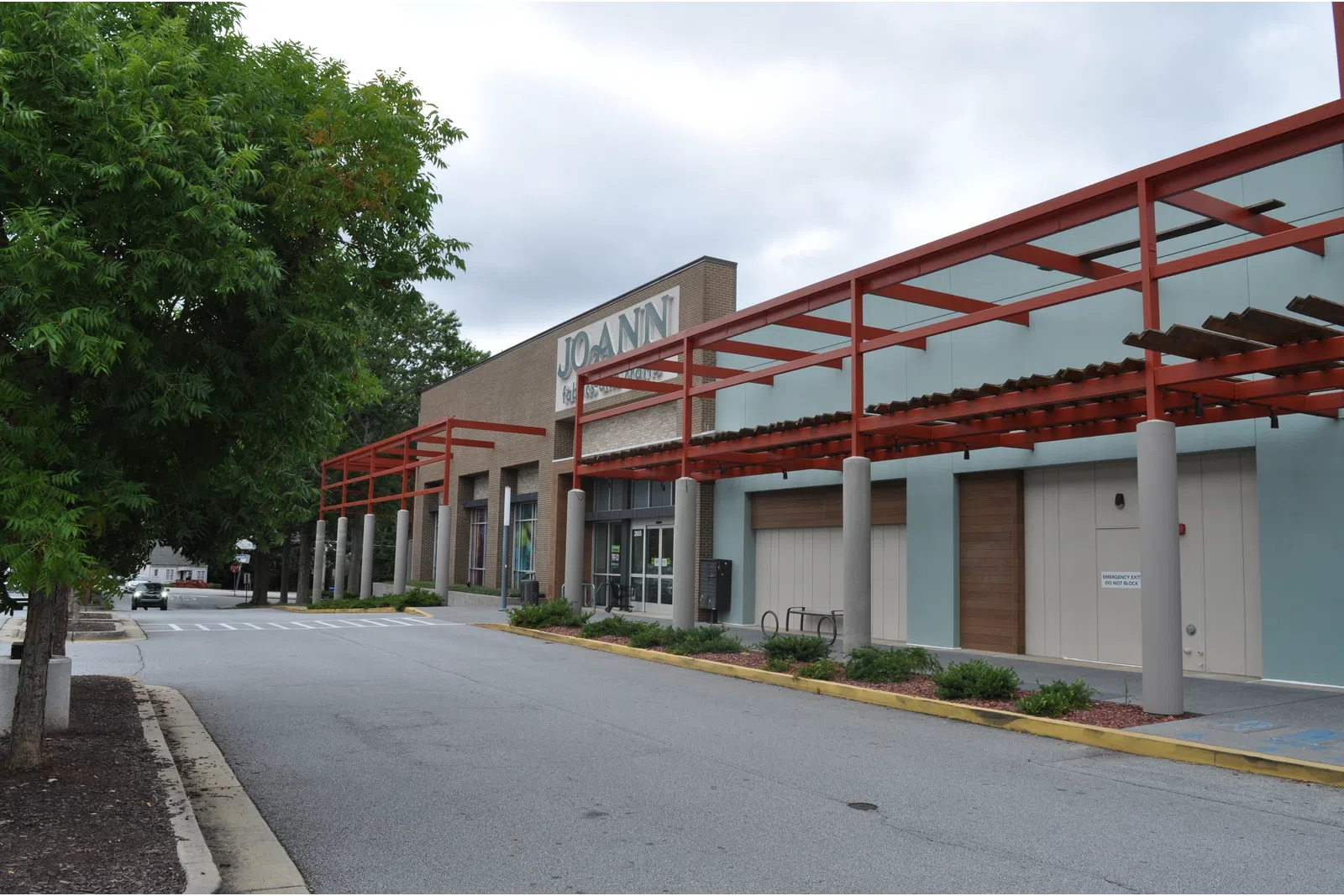Empty street view of a Jo-Ann fabric and craft store with red pergola and overcast sky