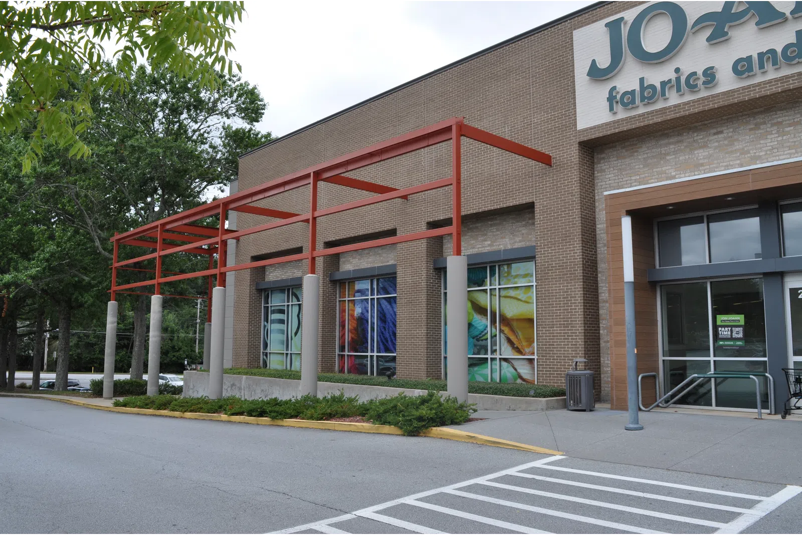 Exterior view of Jo-Ann Fabrics and Crafts store with brick facade and red metal awning structure.