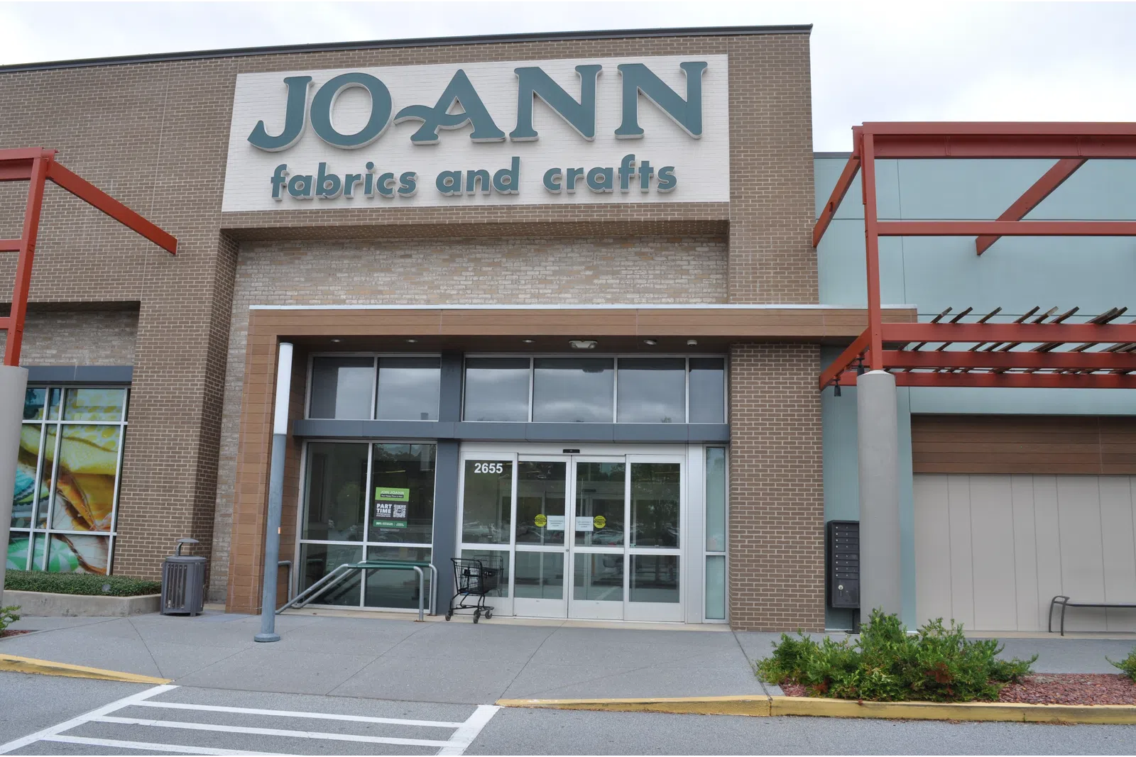 Facade of Jo-Ann Fabrics and Crafts store with glass entrance and exterior signage on a cloudy day