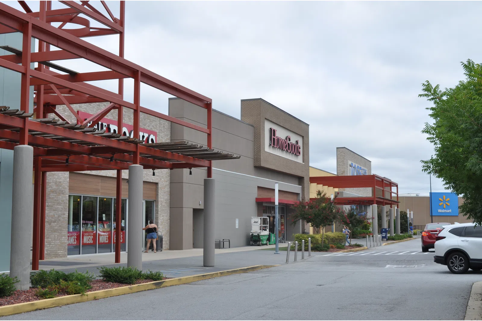 Shopping center exterior with HomeGoods and Walmart stores under a cloudy sky with parked cars.