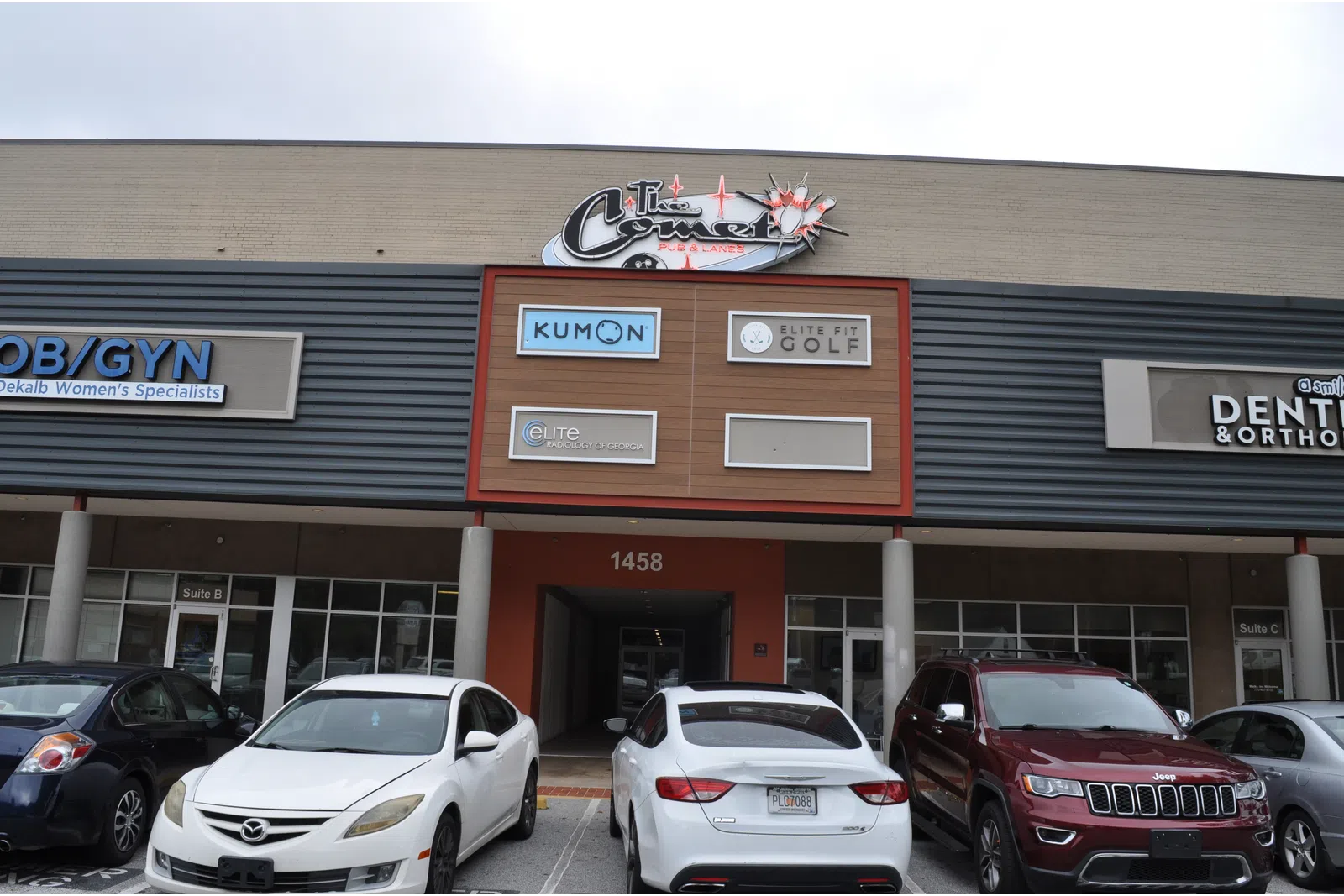 Front view of a commercial building with parked cars and signs for Kumon, Elite Golf, OB/GYN, and dental offices.