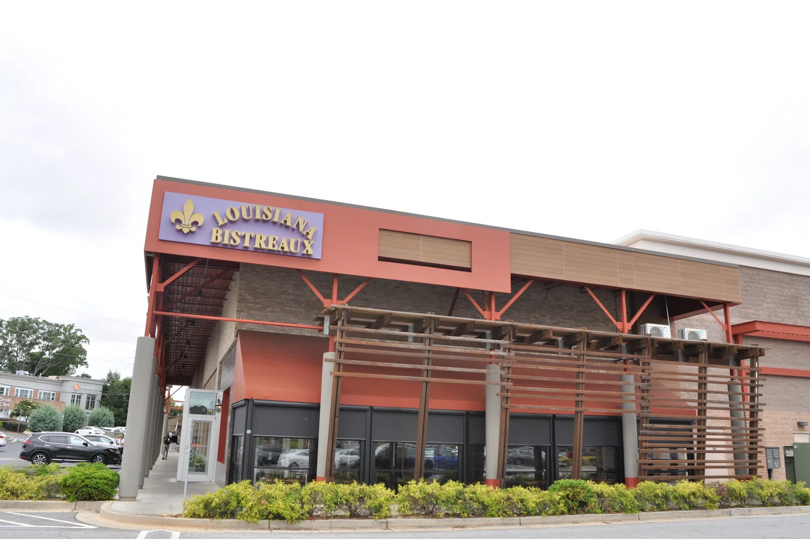 Exterior view of Louisiana Bistreaux restaurant with red and brown facade and wooden pergola structure.