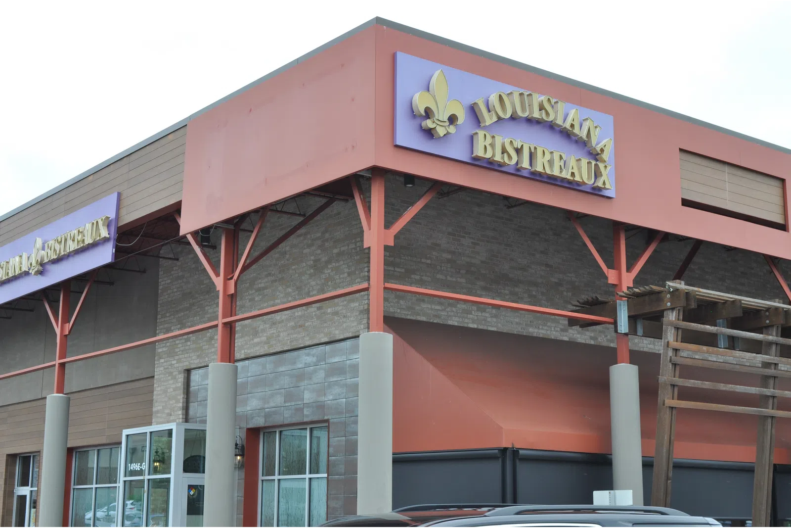 Exterior view of Louisiana Bistreaux restaurant with purple and gold signage on a building corner.