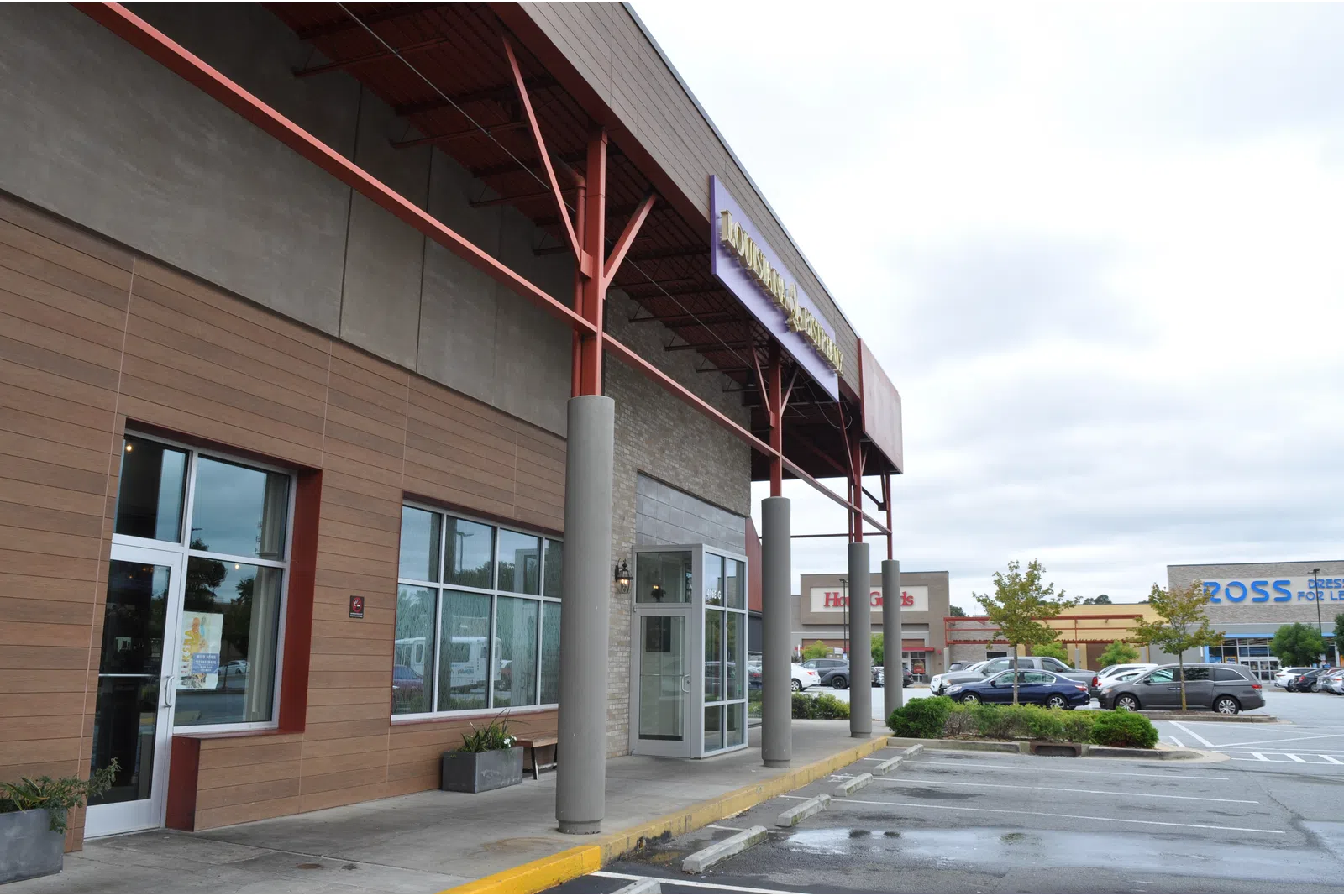 Shopping center with storefronts including Ross Dress for Less and parking lot under cloudy sky.