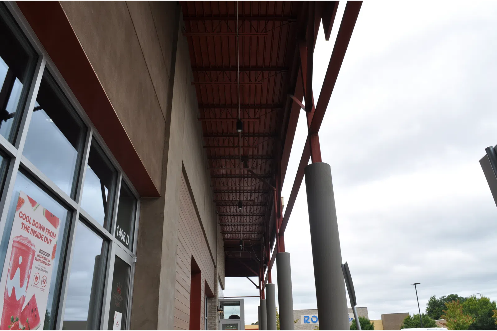 Exterior view of a commercial building entrance with tall pillars and cloudy sky in the background.