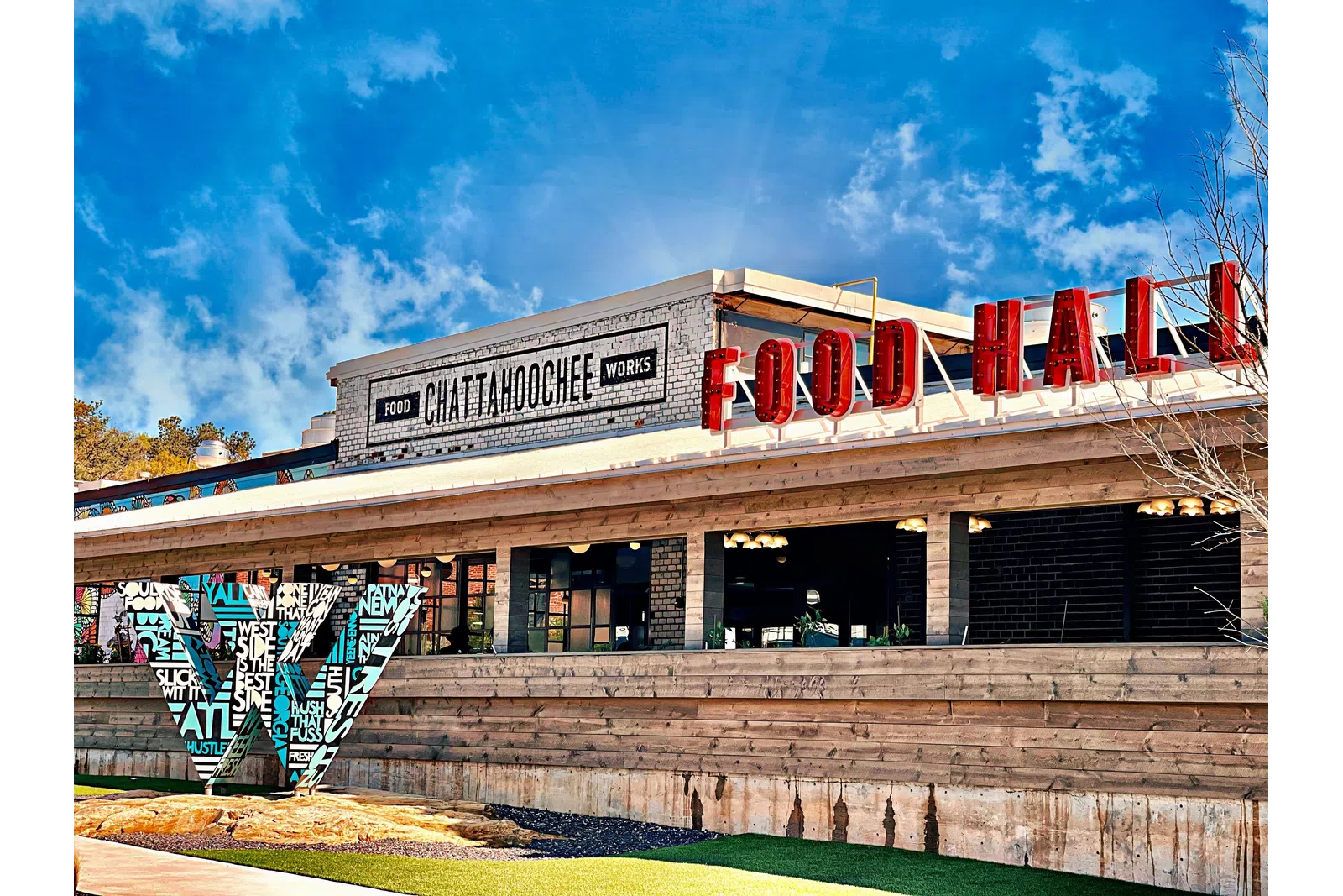Chattahoochee Food Works building with red Food Hall sign under a bright blue sky.