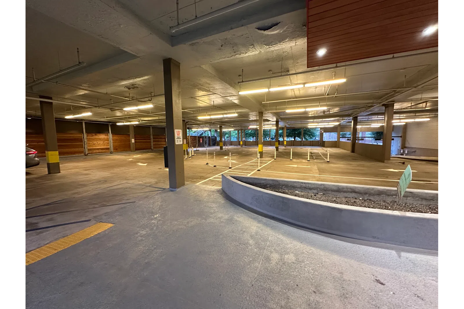 Empty indoor parking garage with concrete pillars, yellow markings, and overhead fluorescent lights