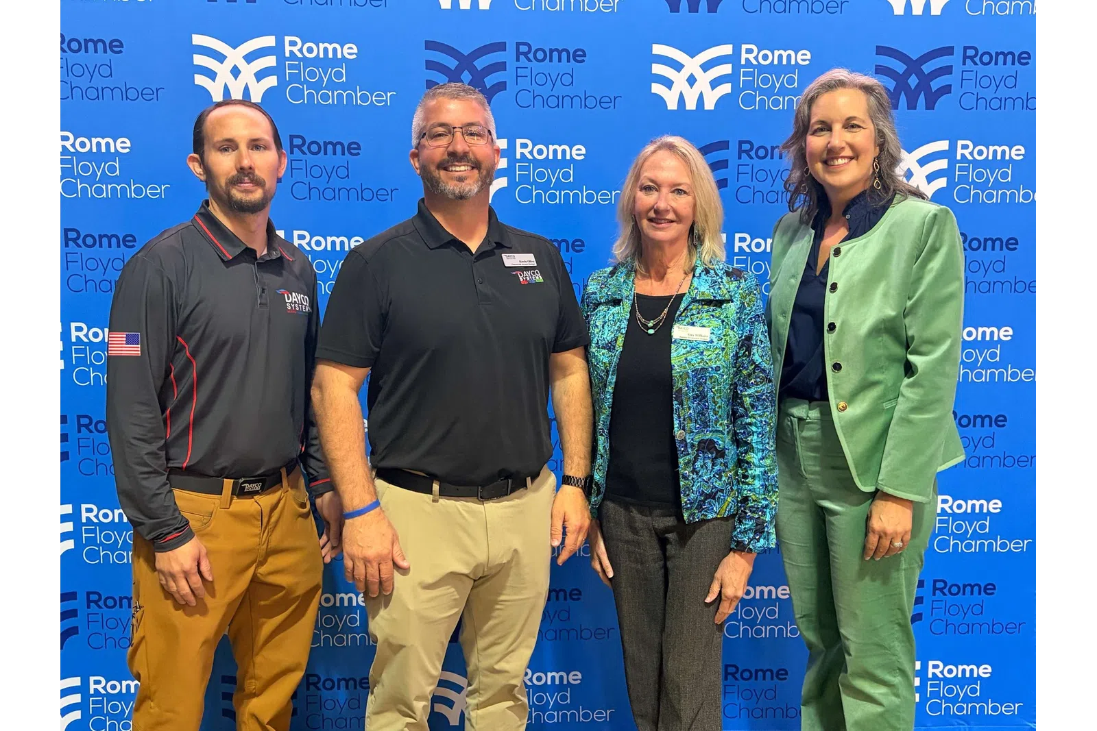 Four professionals standing in front of Rome Floyd Chamber backdrop during an event or meeting.