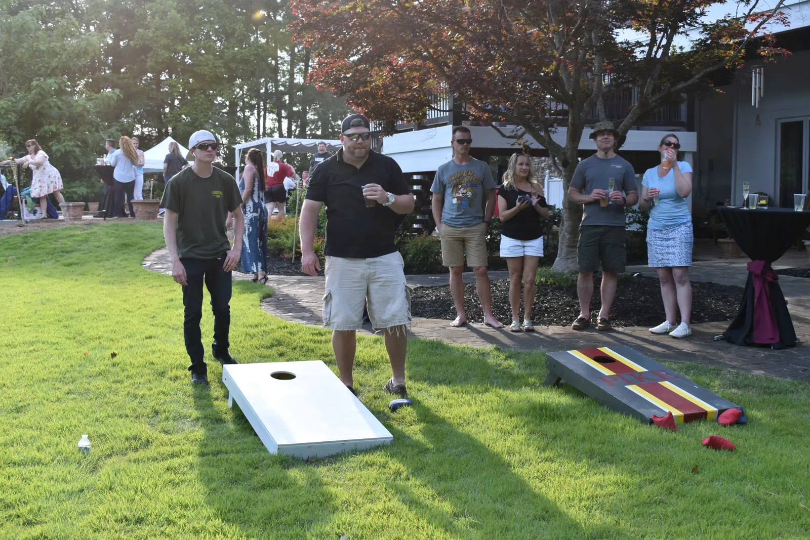 a group of people standing on a lawn with a small pool