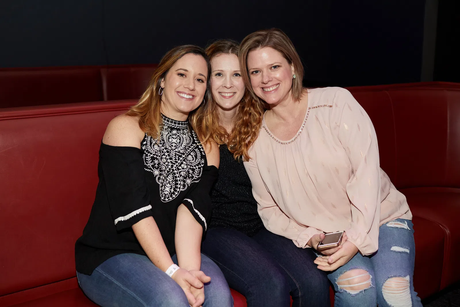 a group of women sitting on a red couch