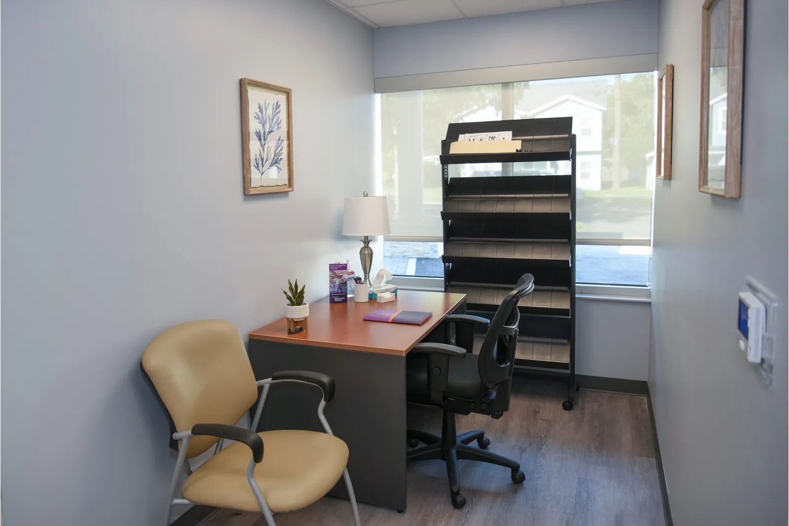 a desk with a chair and a lamp in a room with a window