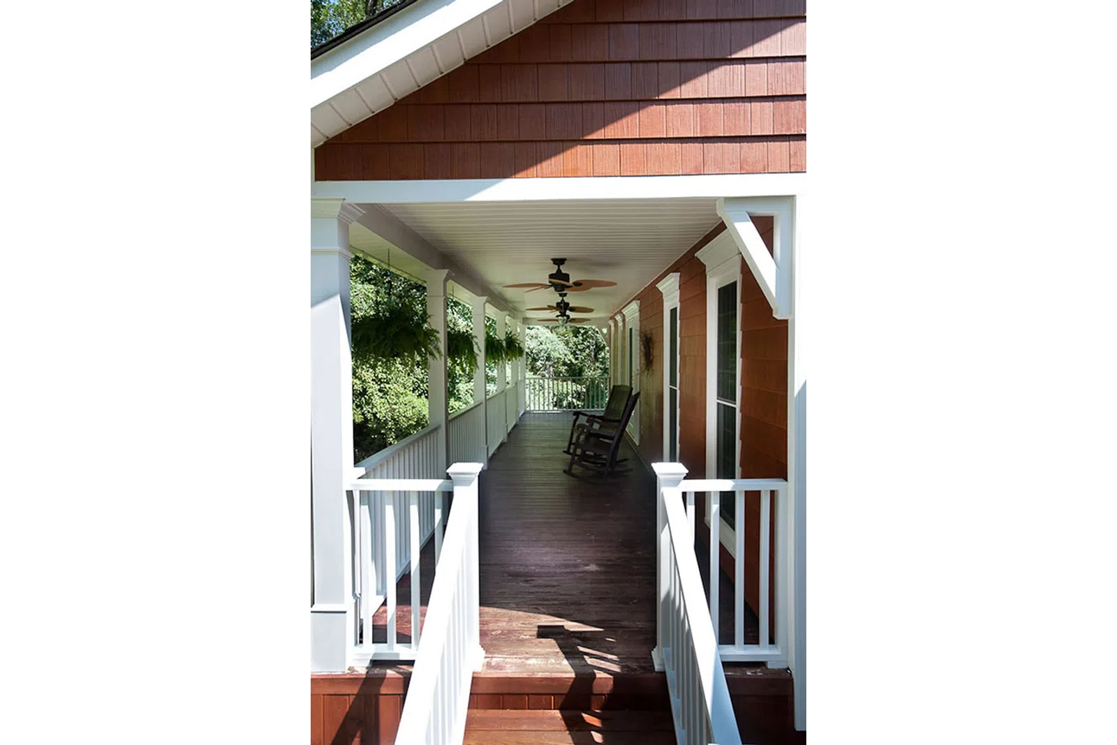 a porch with a wood railing and a wood deck with a chair and a wood railing and a