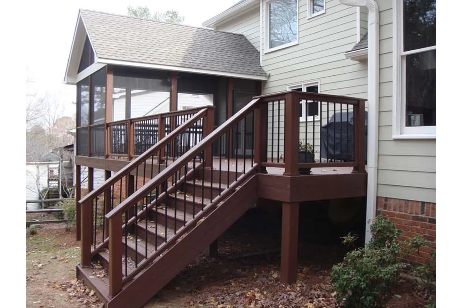 a deck with a railing and a house in the background
