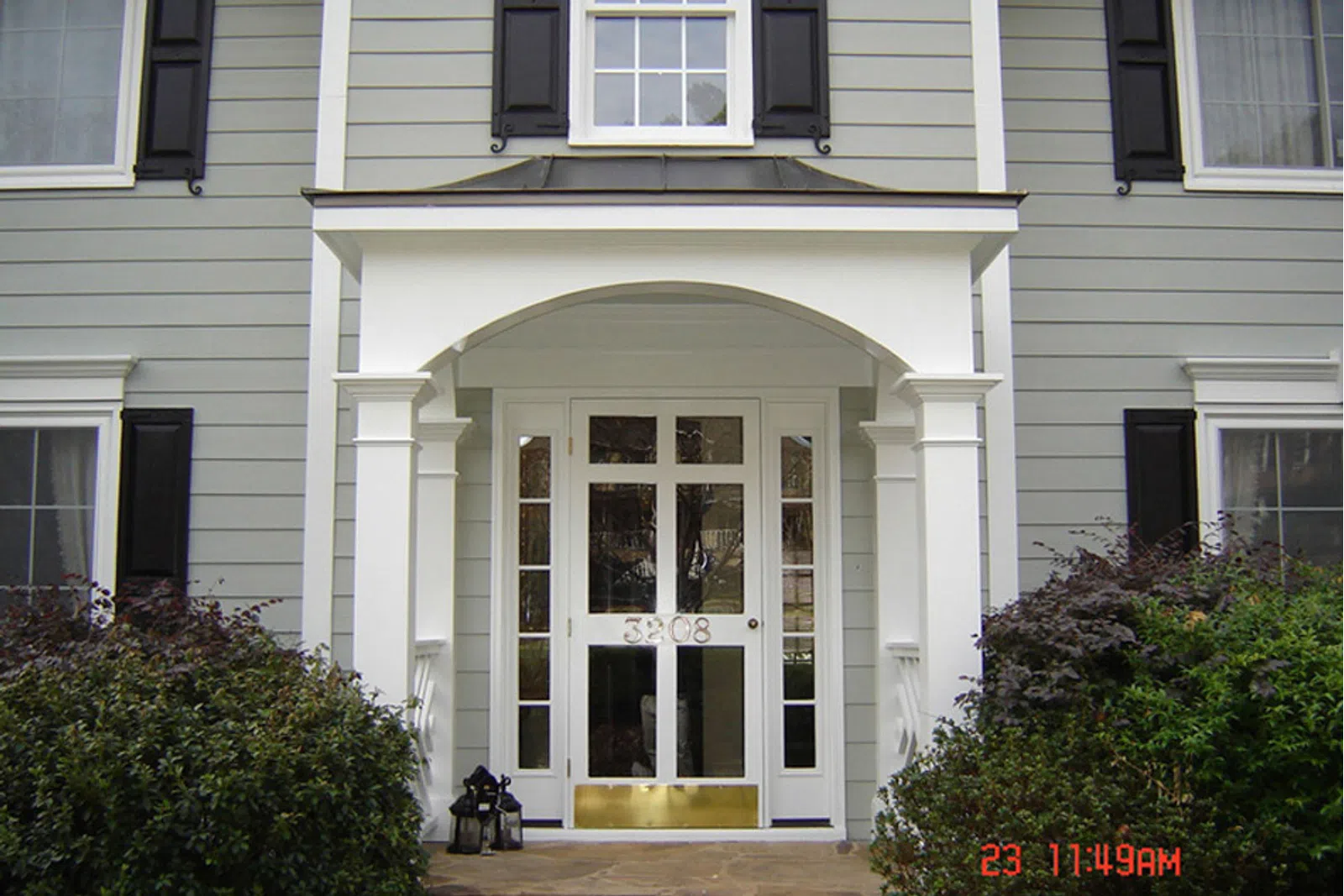a white house with a large front door and bushes in front