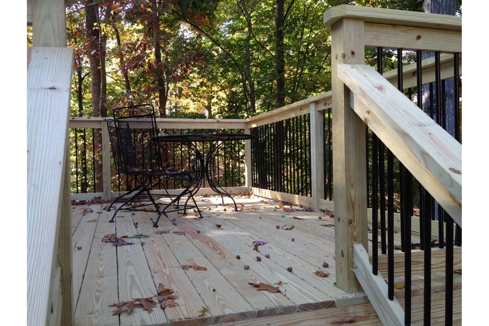 a deck with a chair and a table and trees in the background