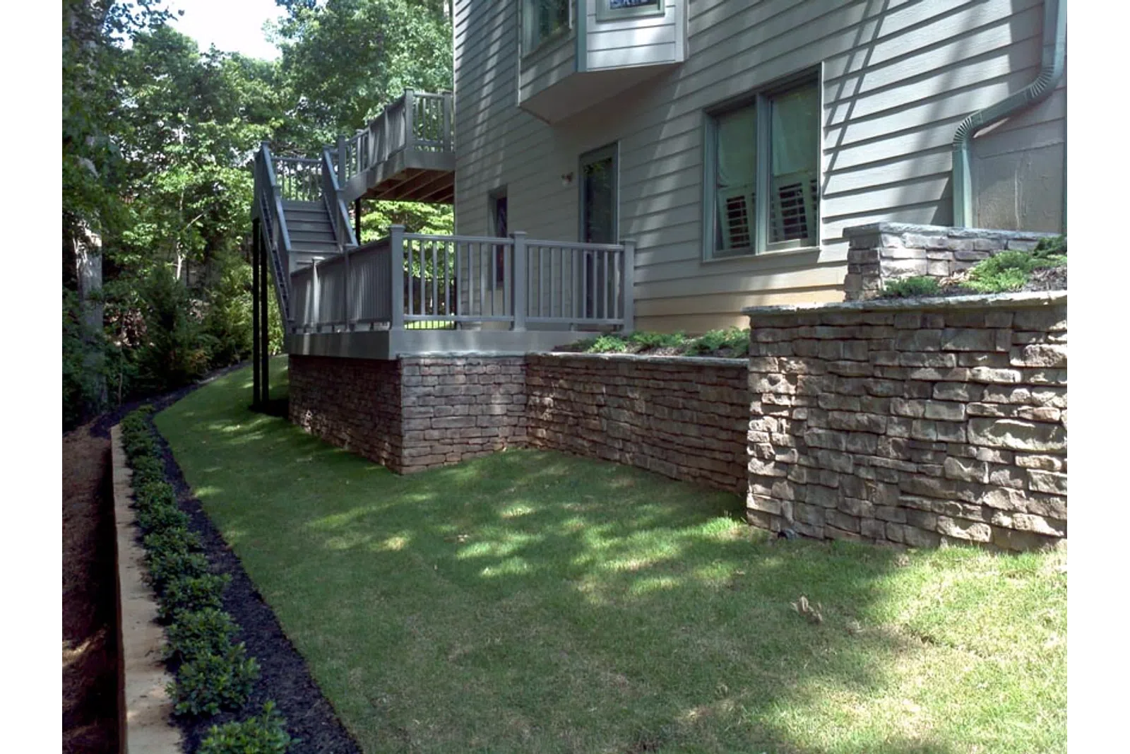 a house with a brick wall and a lawn