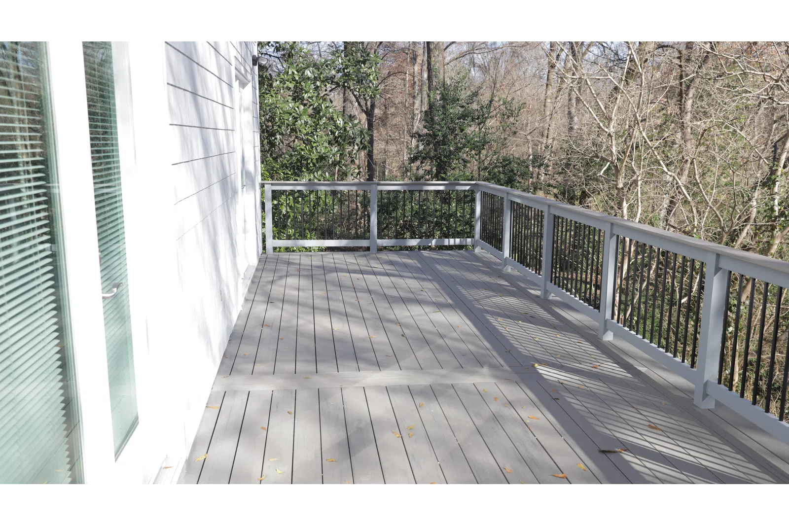 a wooden deck with a railing and trees on the side