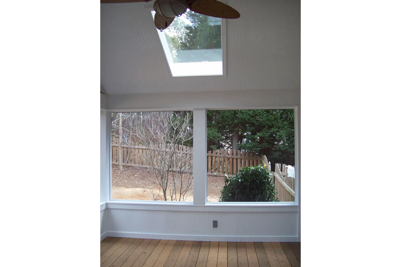 a white porch with a railing and trees outside