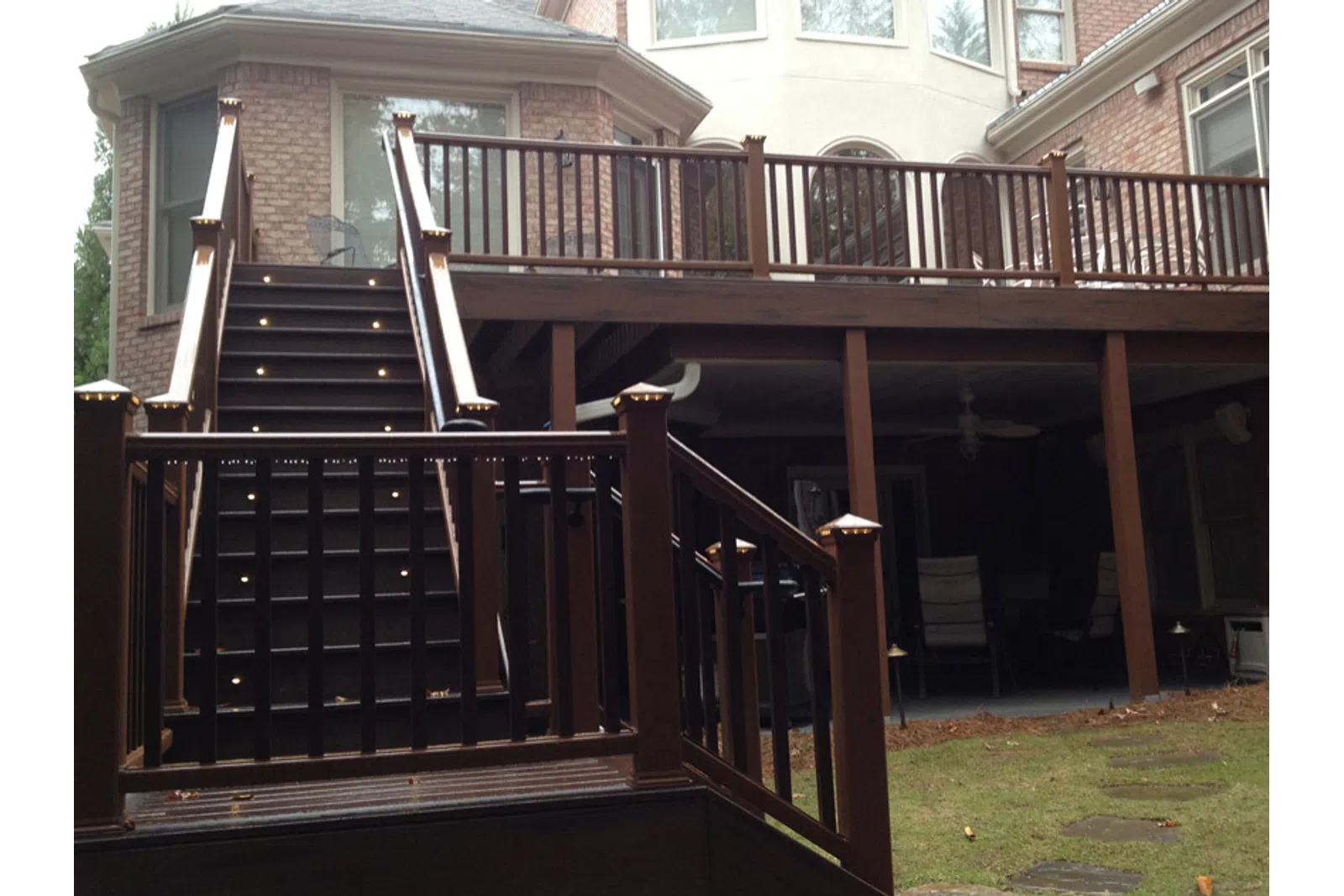 a deck with a railing and a house in the background