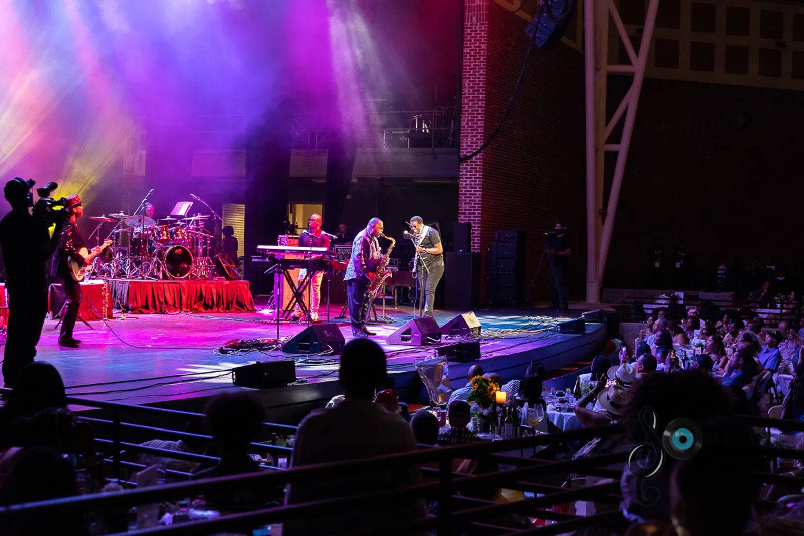 a group of people sitting on stage with stage lights and an audience