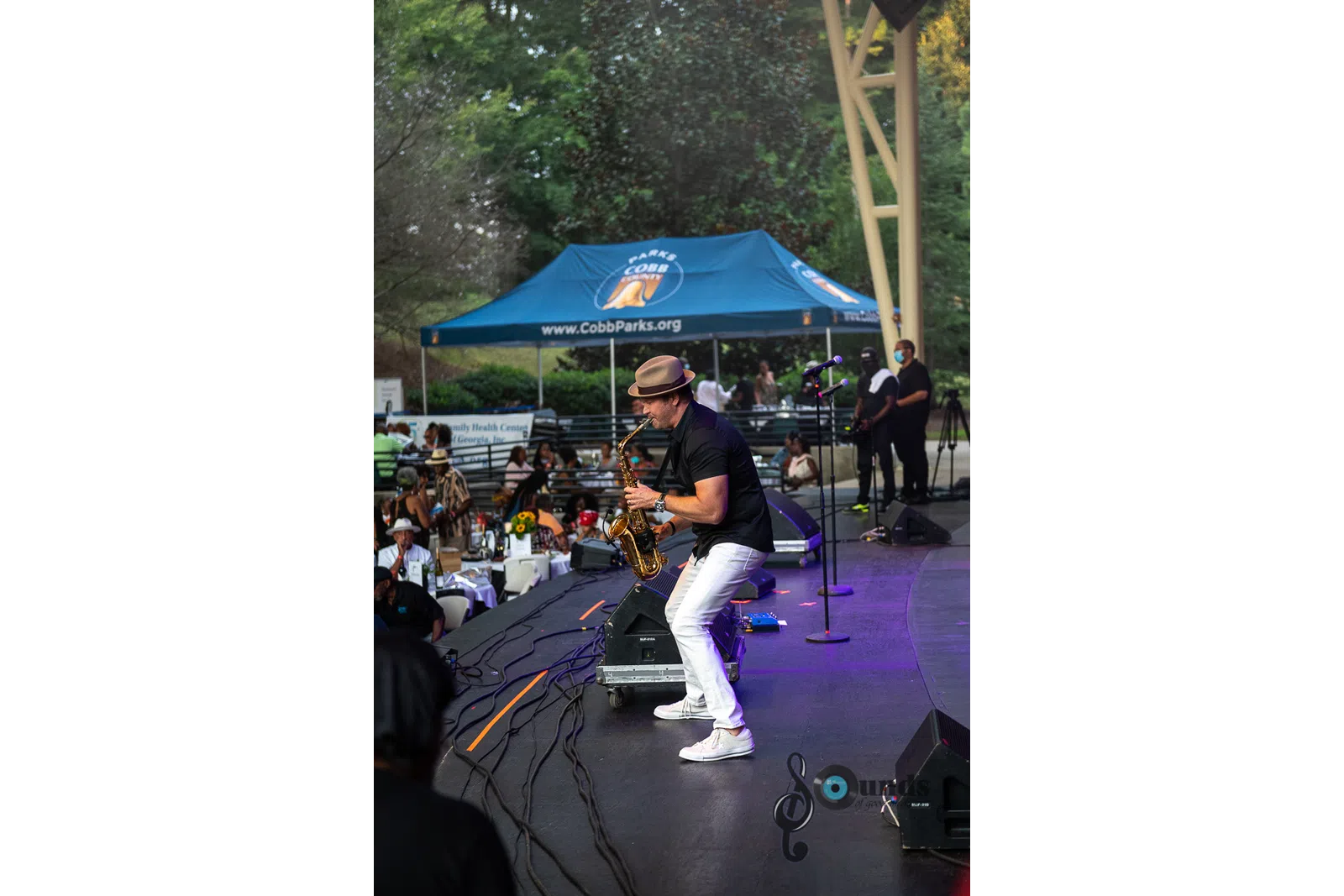 a group of people playing instruments and performing on a stage with an umbrella