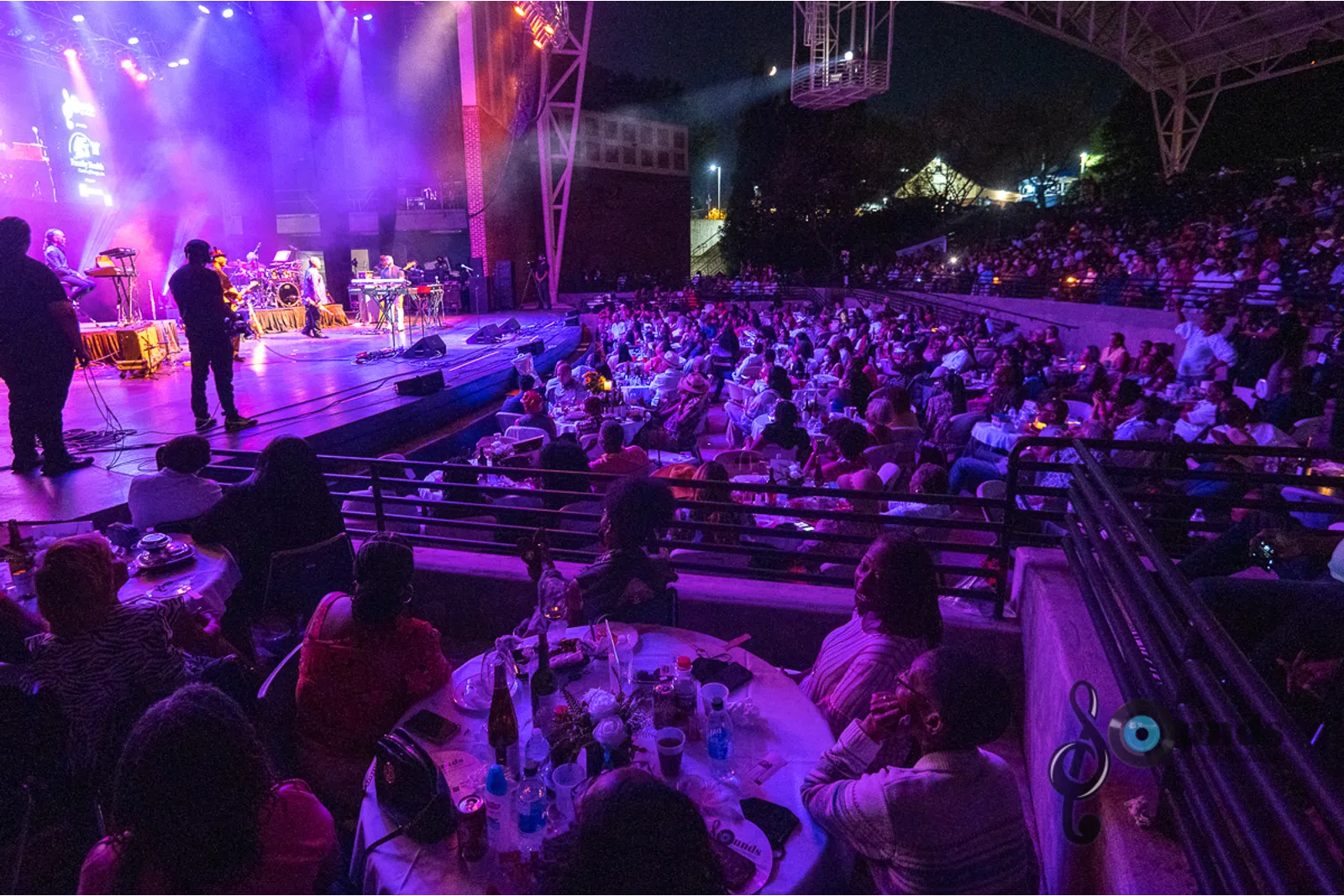 a group of people sitting on stage with stage lights and an audience