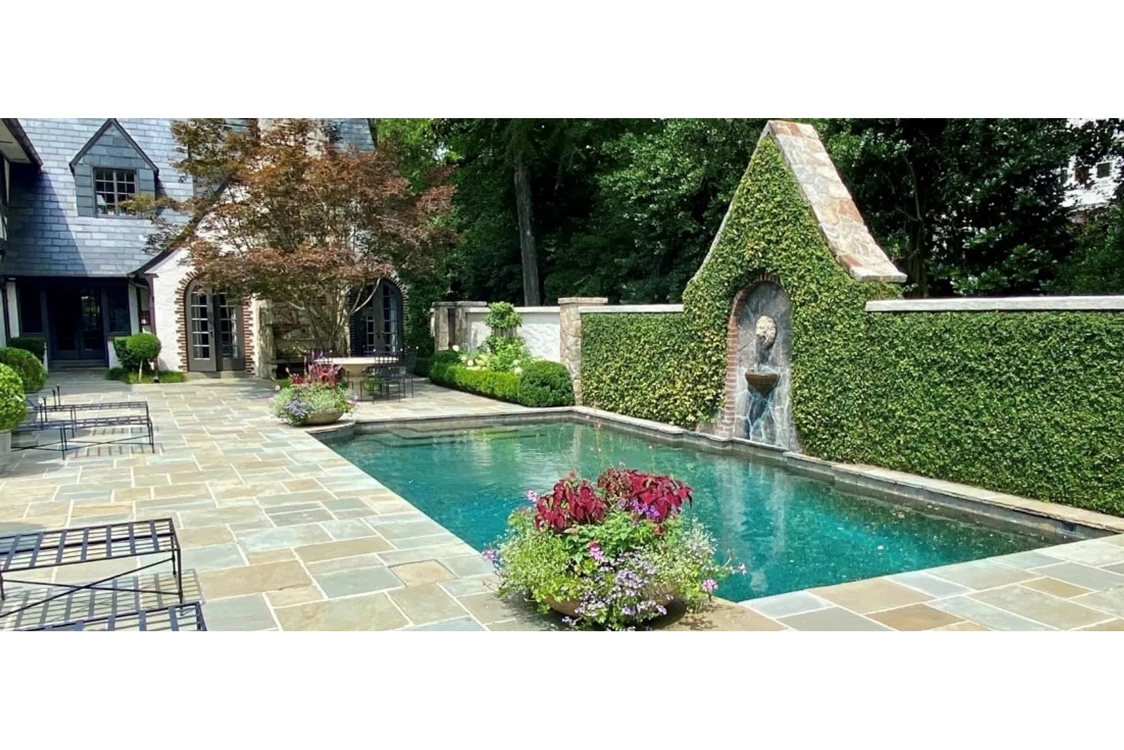 a pool with a statue in the middle of a yard with a house