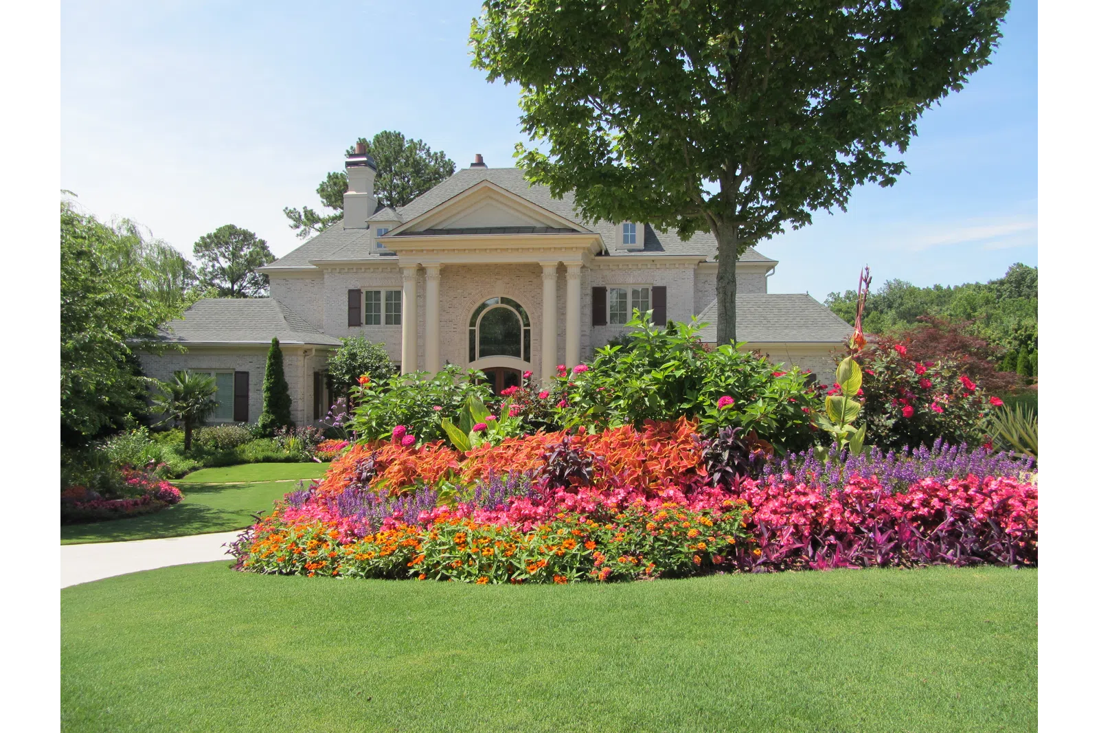 a large house with a large front yard and a large flower bed