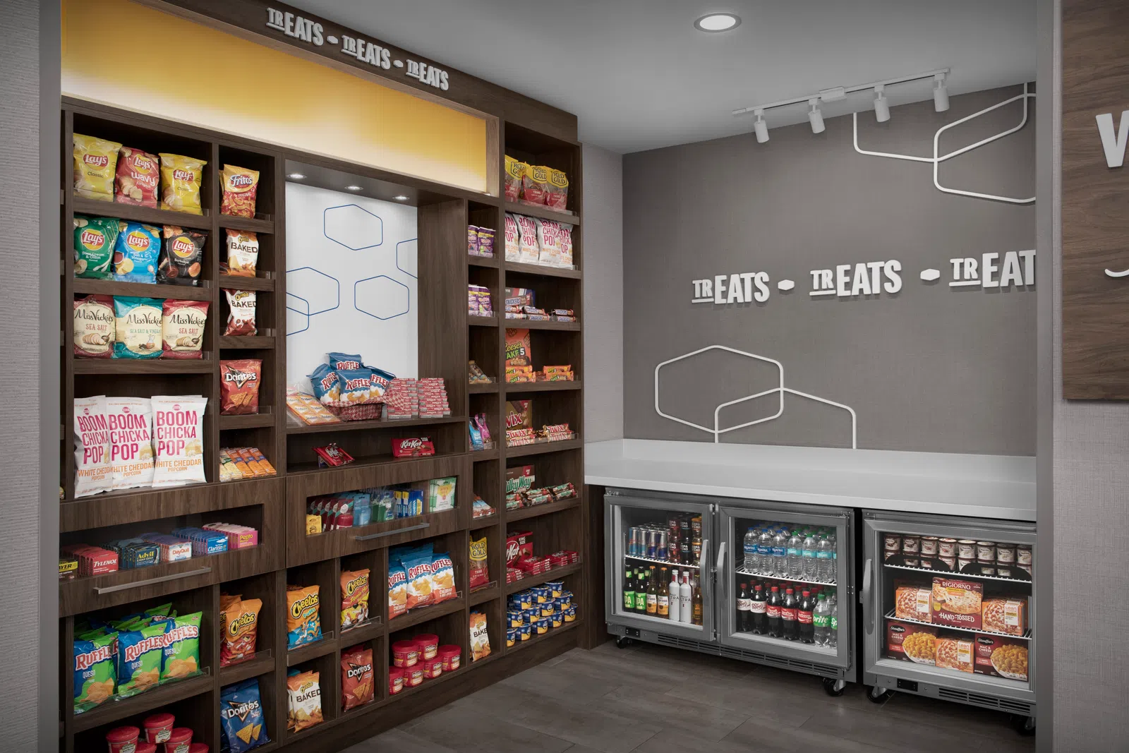 Snack and beverage display with assorted chips, sodas, bottled water, and frozen meals in a modern retail corner.