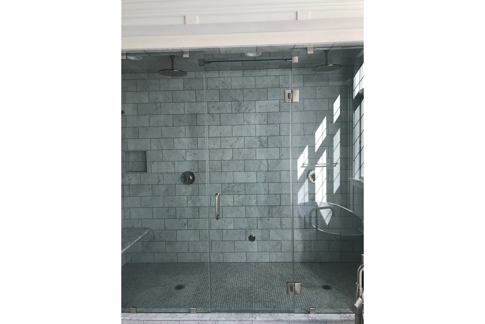 Modern walk-in glass shower with dual rain showerheads and marble tile walls and floor