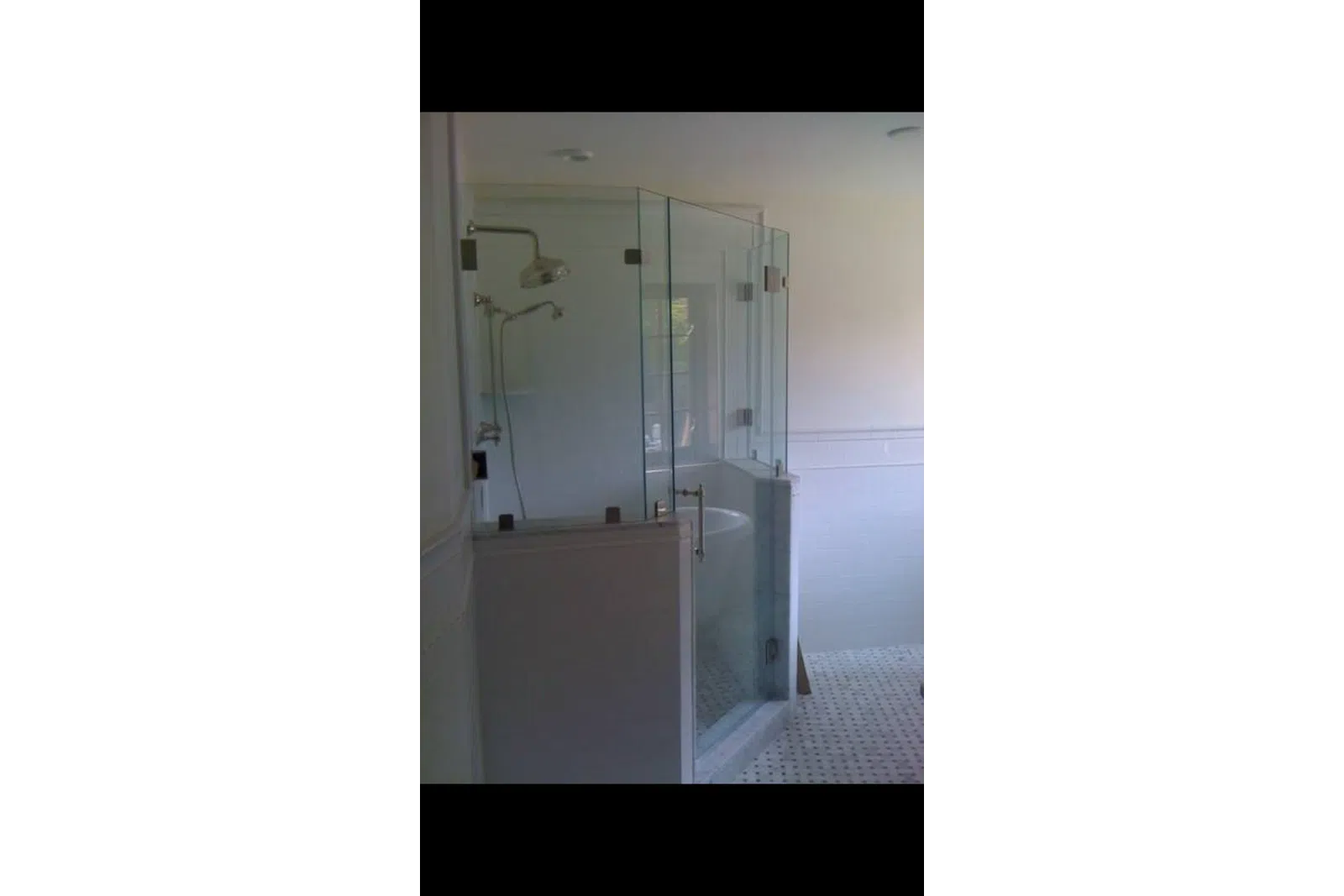 Modern bathroom with glass-enclosed shower and white tiled floor and walls.