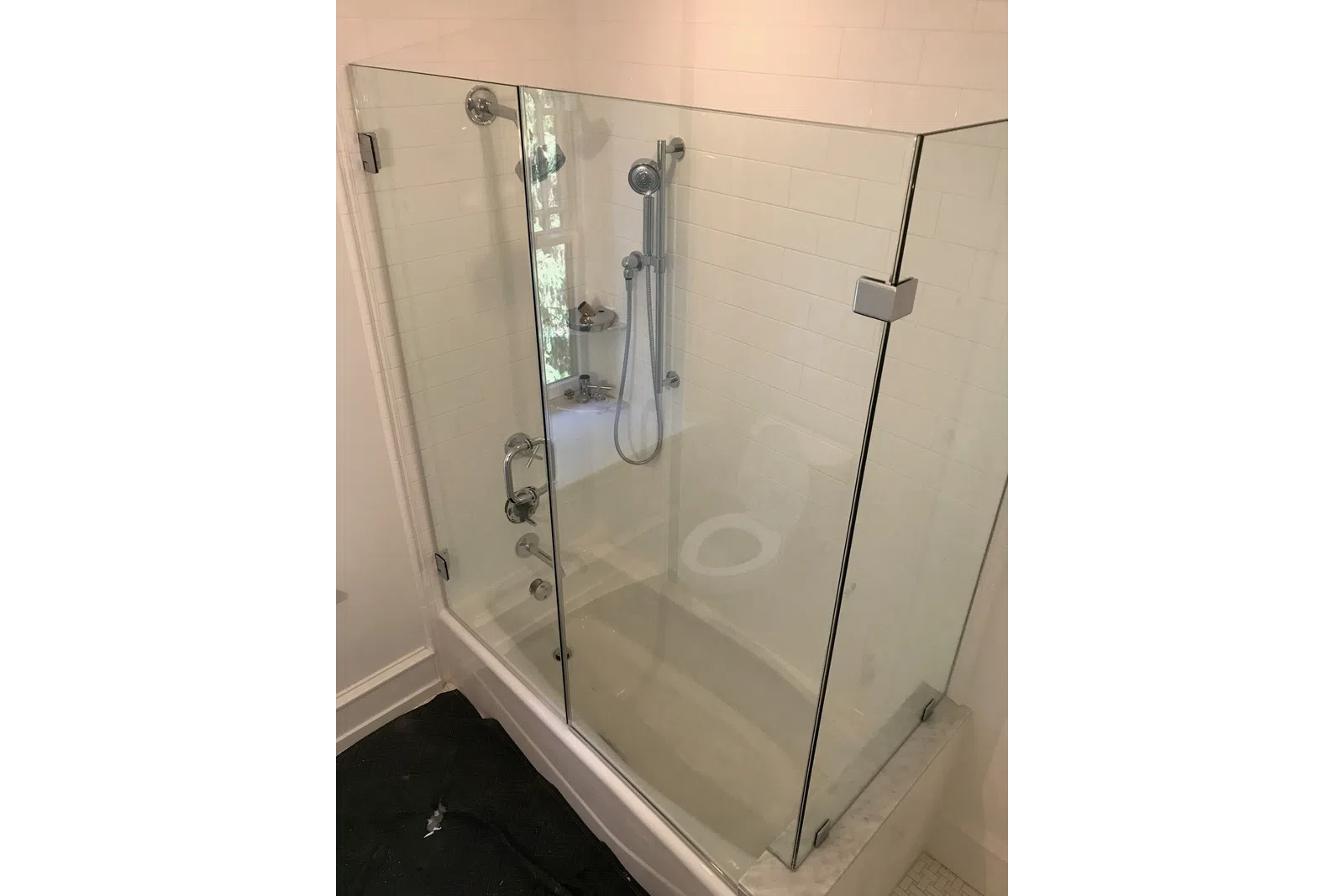 Modern bathroom featuring a glass shower enclosure with chrome fixtures and white tiled walls.