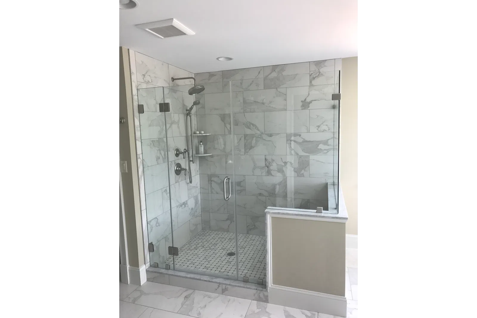 Modern bathroom with glass-enclosed marble shower featuring chrome fixtures and a tiled floor and walls.