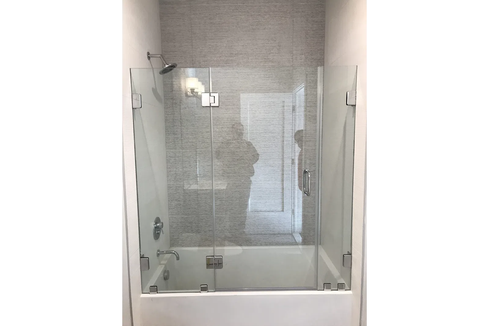 Modern bathroom with a glass shower enclosure, rain shower head, and bathtub in a neutral color scheme.