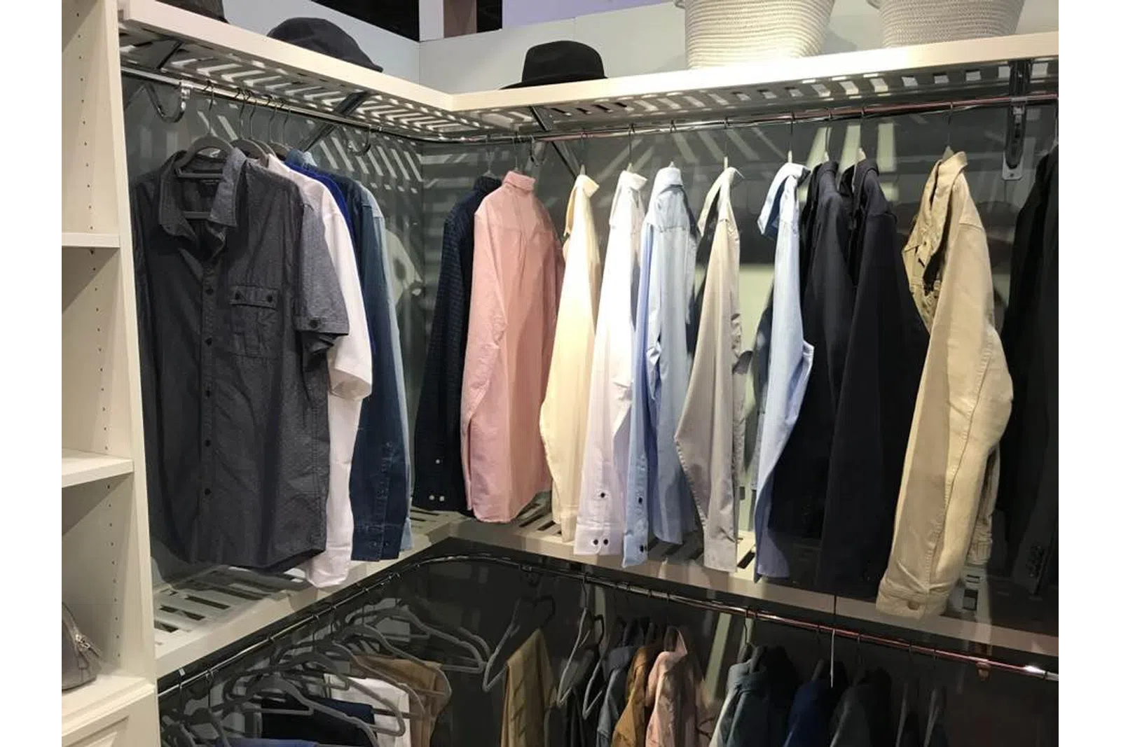 Organized closet with various men's shirts and jackets hanging on racks with shelves on the side.