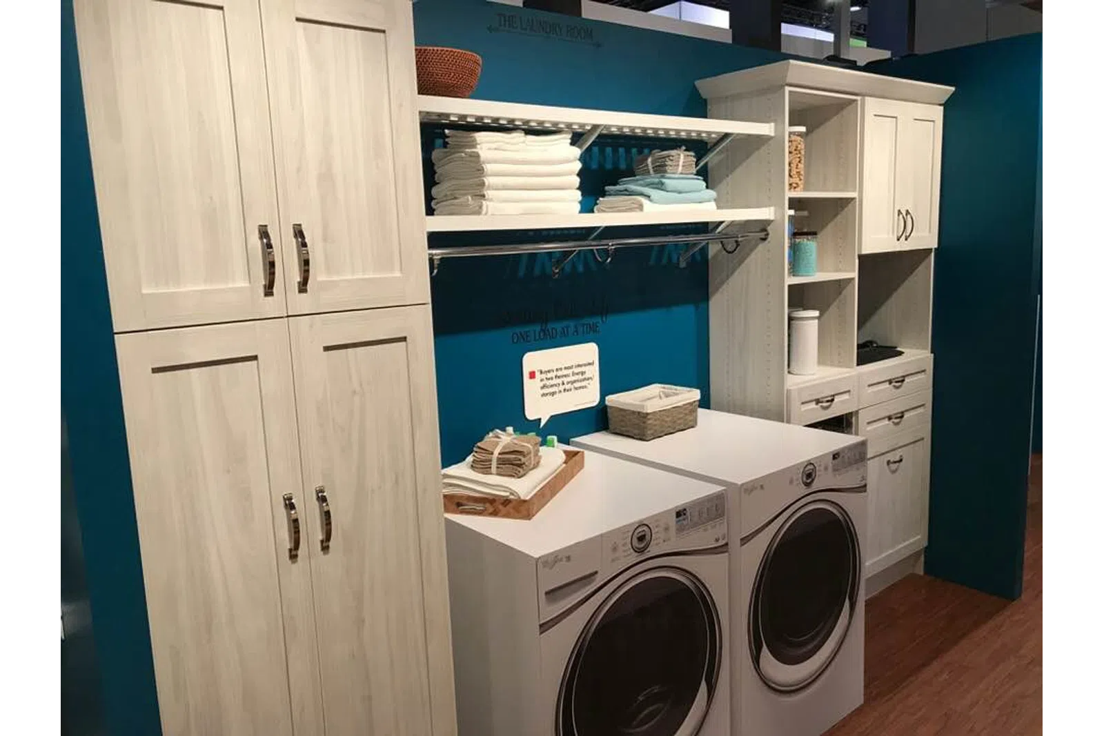 Modern laundry room with white cabinets, stacked towels, and front-loading washer and dryer units