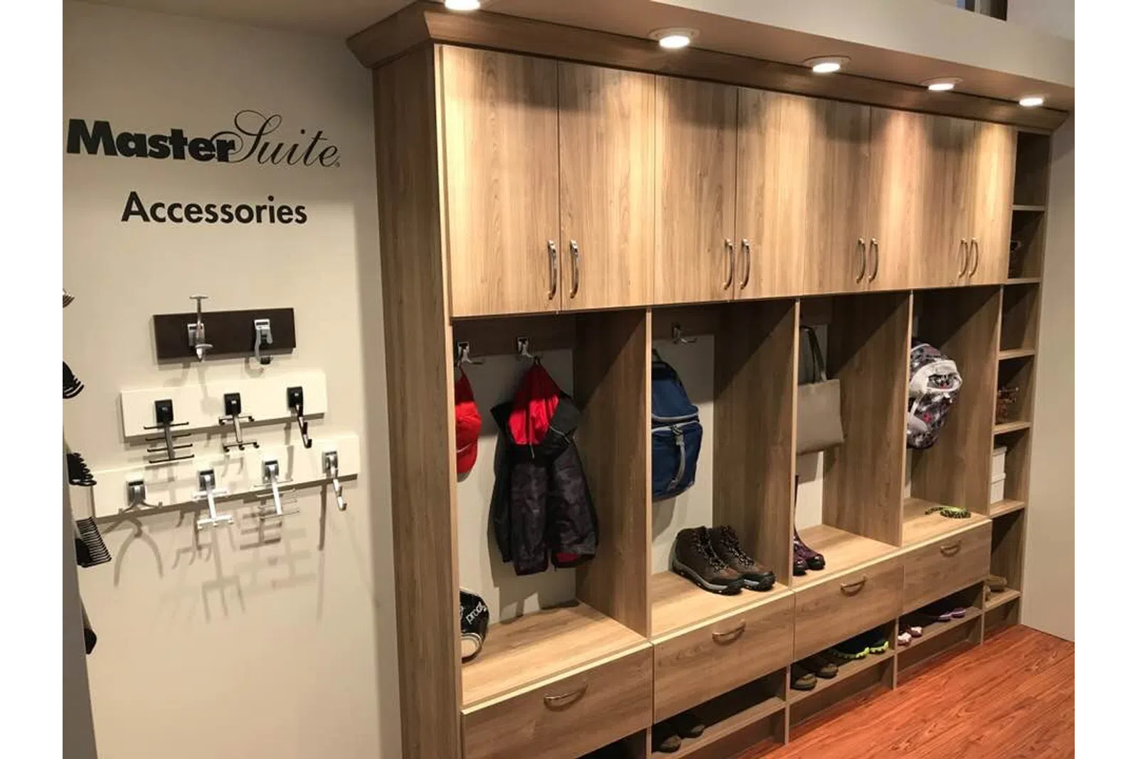 Wooden master suite storage with cabinets, hanging jackets, backpacks, shoes, and closet accessories on display.