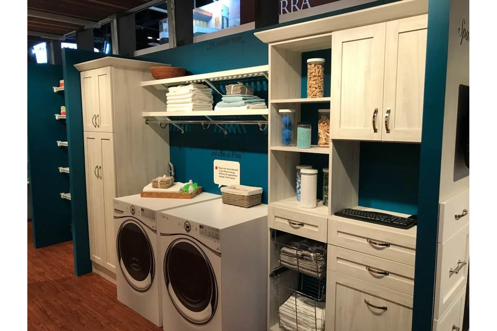 Modern laundry room with front-load washer and dryer, organized shelves, cabinets, and folded towels.