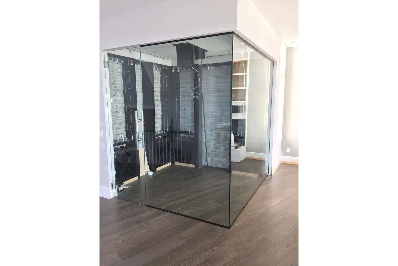Modern empty glass-enclosed office corner with wooden flooring and white walls in a bright space