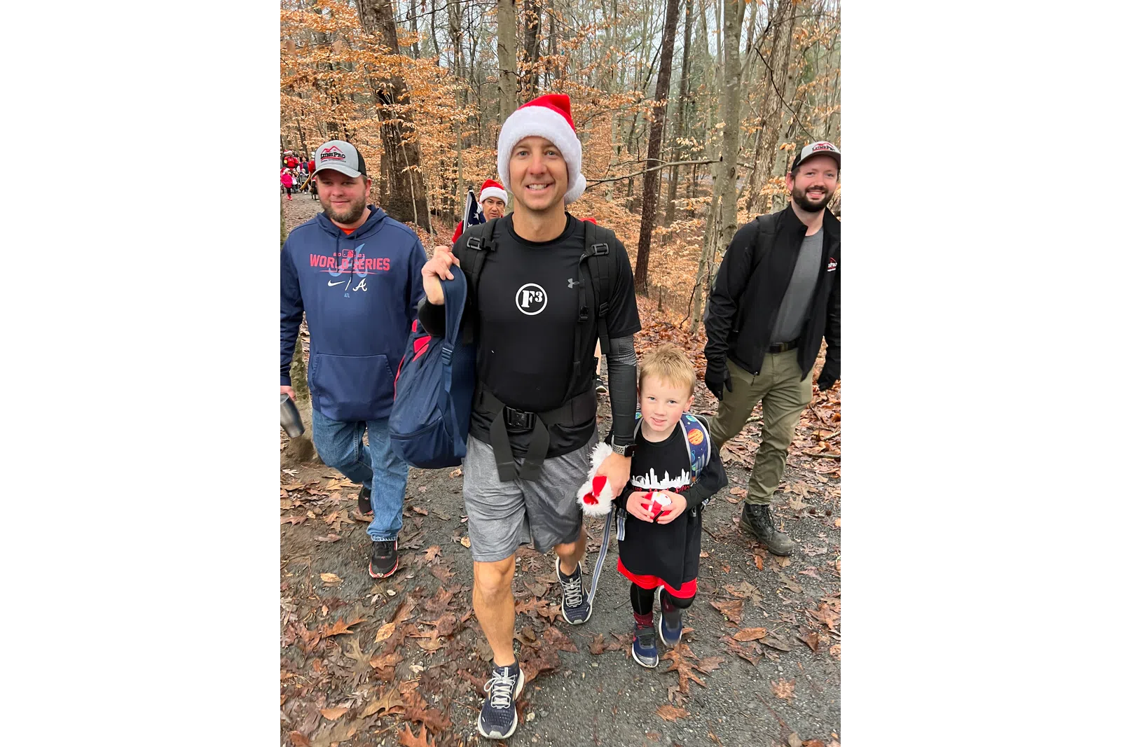 a group of people walking on a trail in the woods