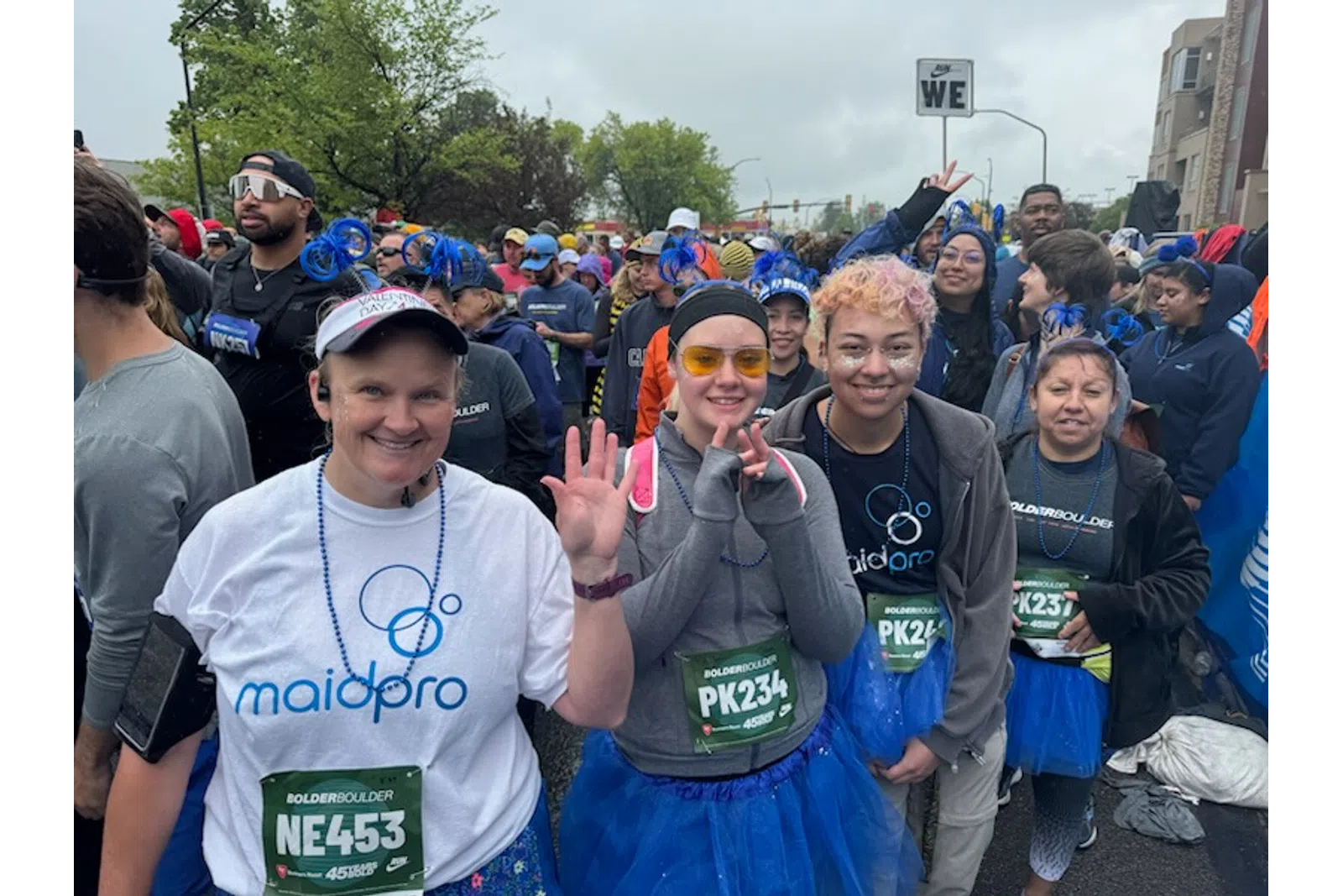 Group of diverse runners in race gear and blue tutus smiling and posing before the Bolder Boulder race.