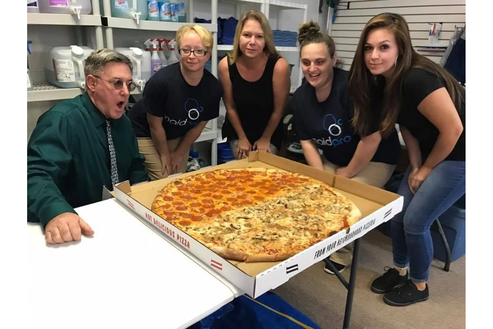 a group of people around a large pizza