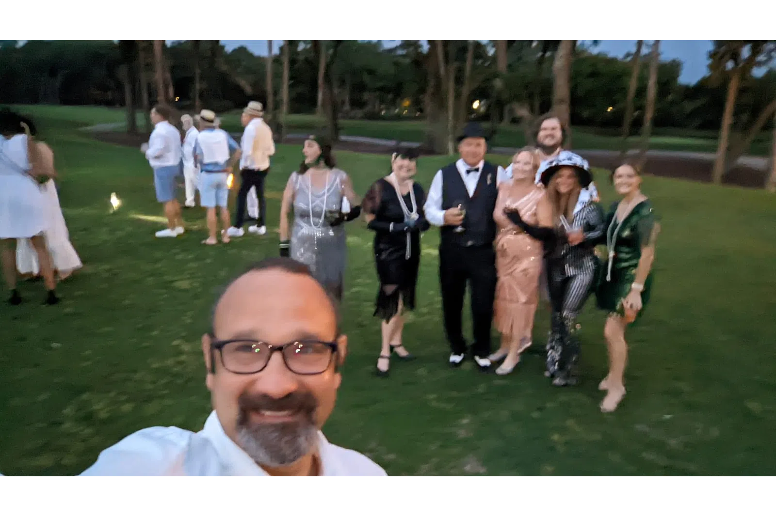 a person taking a selfie with a group of people in the background
